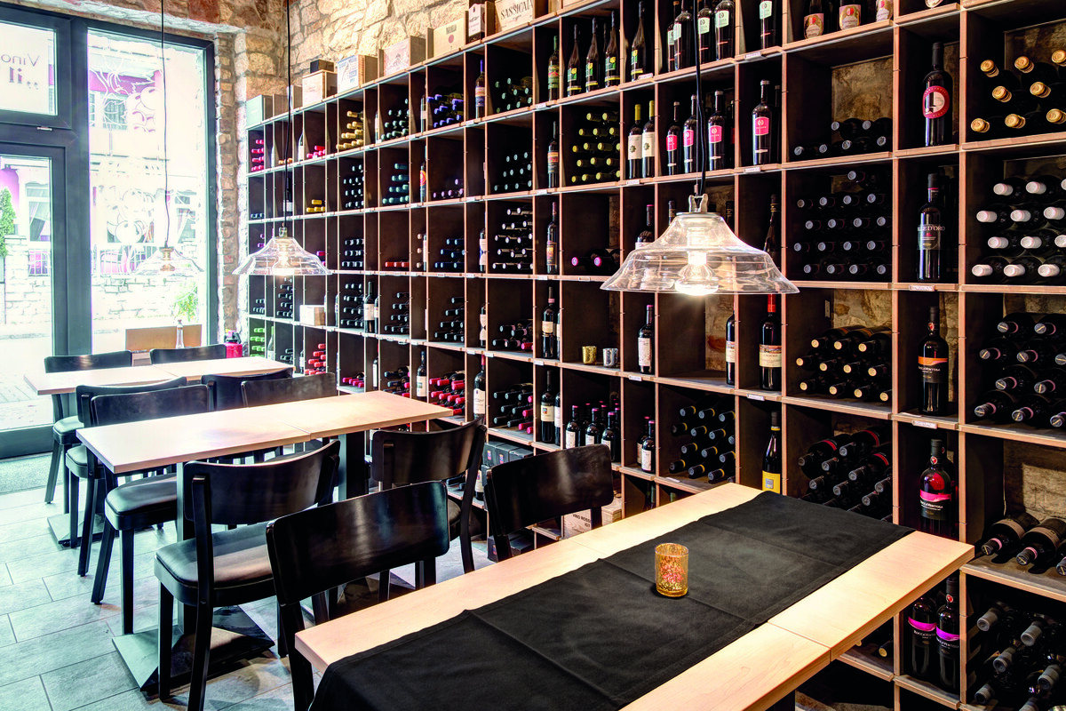 Rohe Steinmauern, gedämpftes Licht und beste Weine verleihen der Vinothek ihr italienisches Flair. Das von Seipp Wohnen geplante Weinregal präsentiert die erlesenen Weine wirkungsvoll. Die drei Bereiche der Lounge - Arbeiten, Verpflegung und Erholung - sind mit hochwertigsten Materialien ausgestattet. Der Fußboden harmoniert mit warmen und gedeckten Wandfarben, die dezente Beleuchtung schafft eine behagliche Stimmung. Die edle Möblierung kombiniert Klassiker, z.B. von Jean Prouvé, mit neuen Entwürfen und lädt zum Verweilen und Entspannen ein.